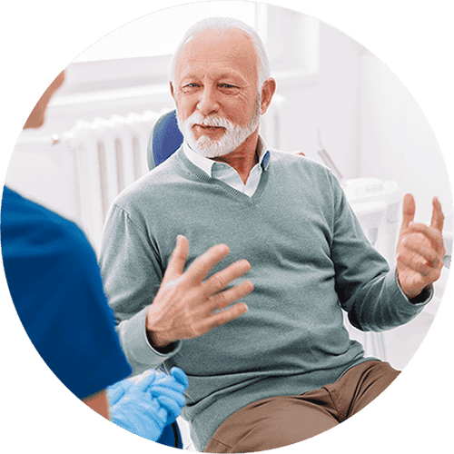 Senior man discussing geriatric dental care options with a dentist in a modern dental office