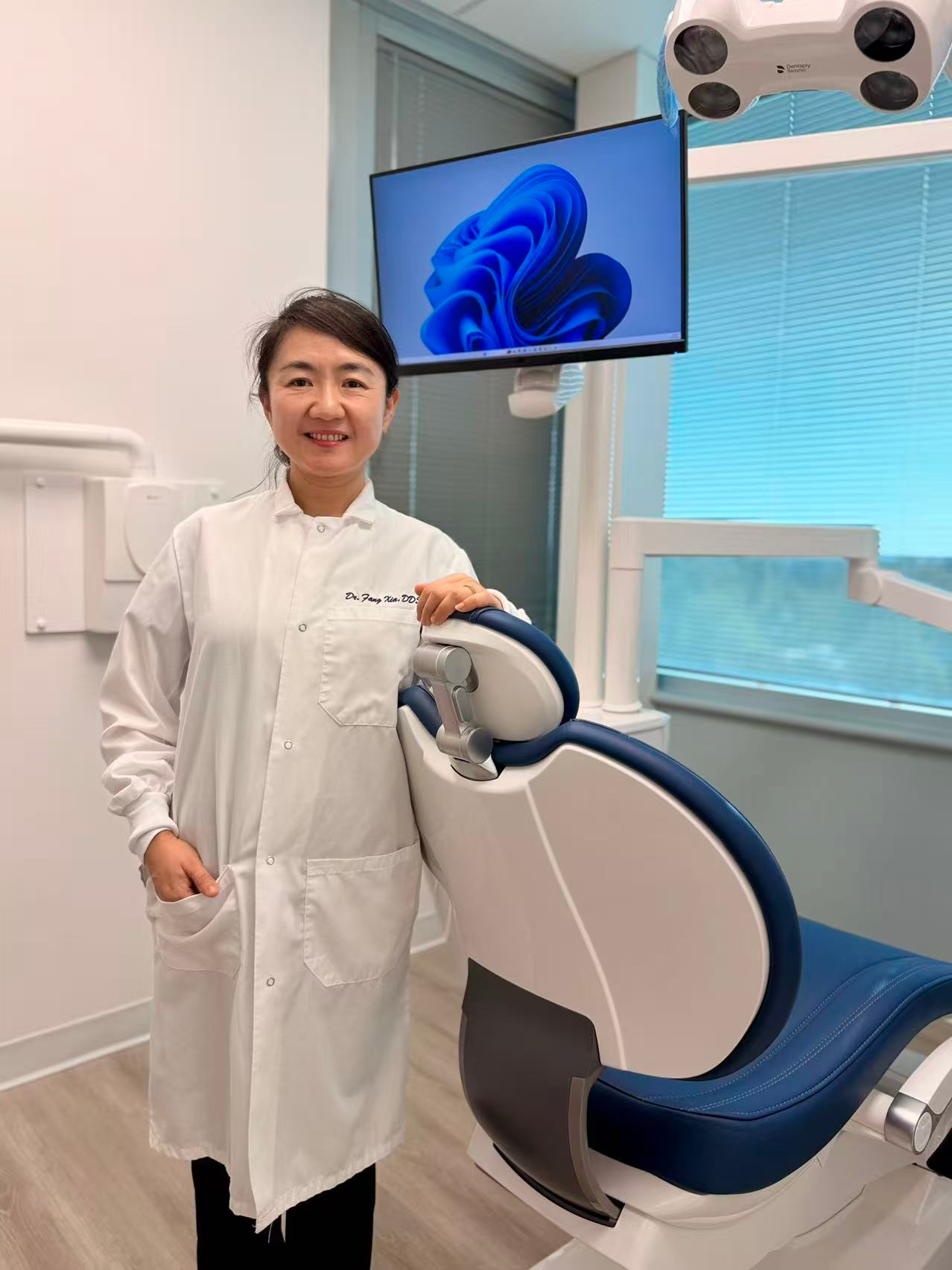 Dr. Xia, a dentist at Best Smile 4U Dentistry, standing beside a modern dental chair in her clinic